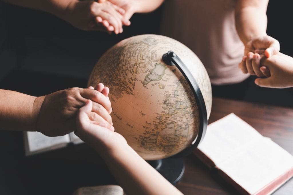 A-group-holding-hands-and-praying-around-a-globe